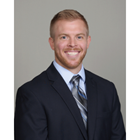 Garrett Gilbert smiles in a black suite in front of a gray background. 